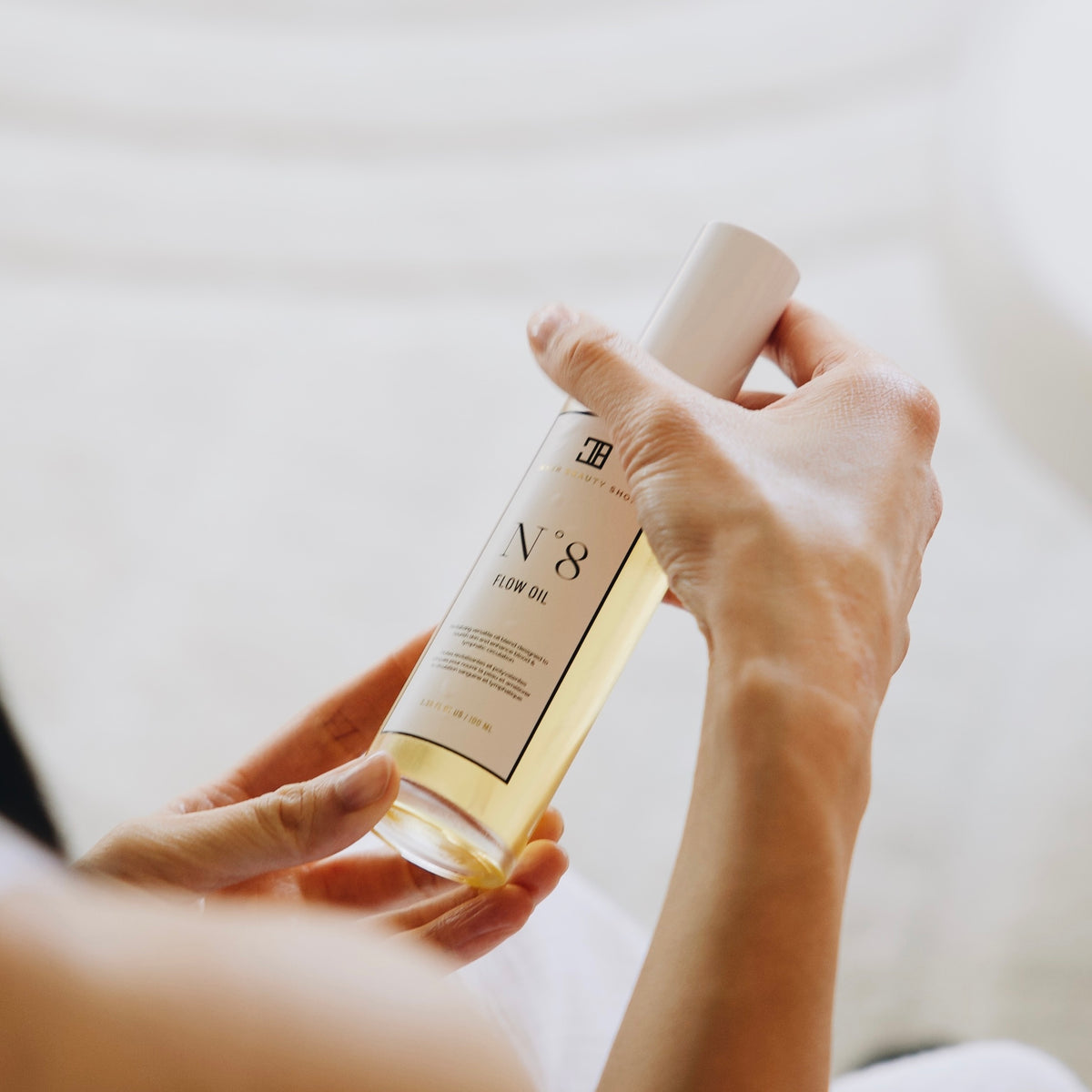 Hands holding a bottle of N°8 Flow Oil