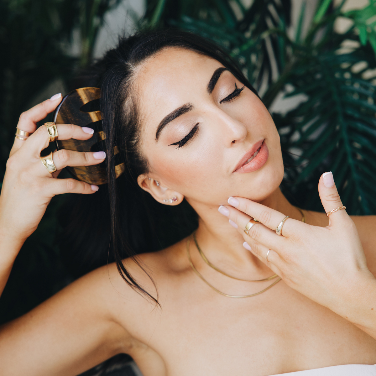 Woman using the tiger's eye gua sha comb on her scalp