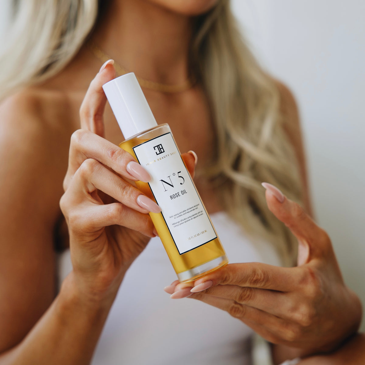 Hands holding a bottle of N°5 Rose Oil
